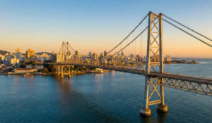 Daytime panoramic view of the Hercílio Luz suspension bridge in Florianópolis, Santa Catarina, connecting the island to the mainland over blue waters.